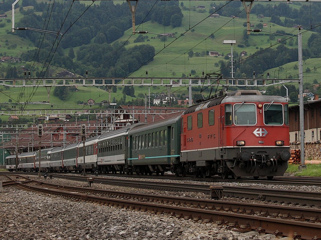 Die Re 4/4 11133 mit einem IR am 27.06.2009 bei der Ausfahrt aus Schwyz.
