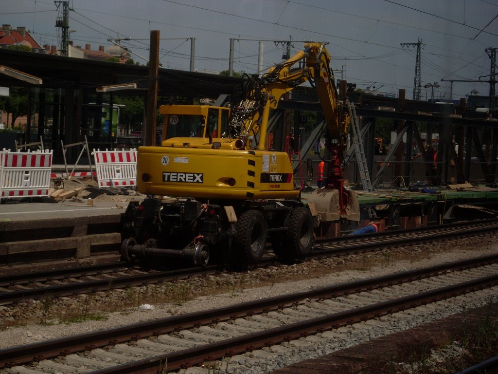 Mnchen Ostbahnhof am 05.06.2011. Der Bagger bei Arbeiten am Bahnsteig.
Vor dem Bagger liegt ein Arbeiter am Bahnsteig und Schweit die Streben.