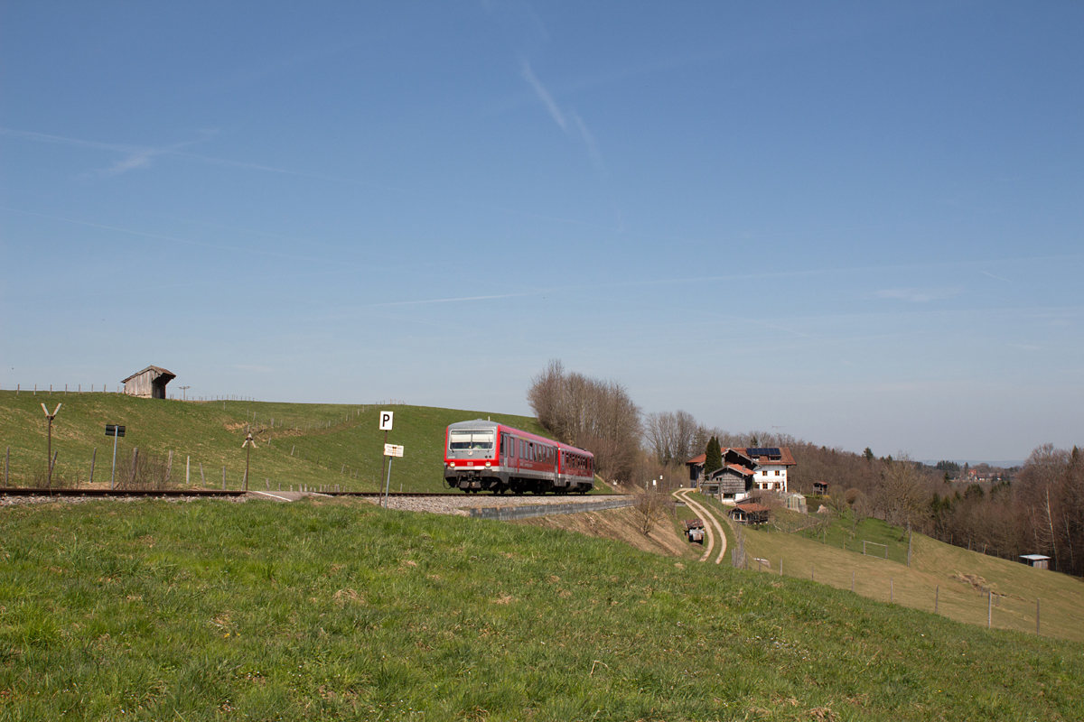 Die Gegend um Waging am See ist geprägt von vielen steilen Hügeln, um die sich die Eisenbahn schlängelt.
Am 10.04.15 ist 628 628-0 gerade um die Mittagszeit von erstgenanntem Kurort nach Traunstein unterwegs.