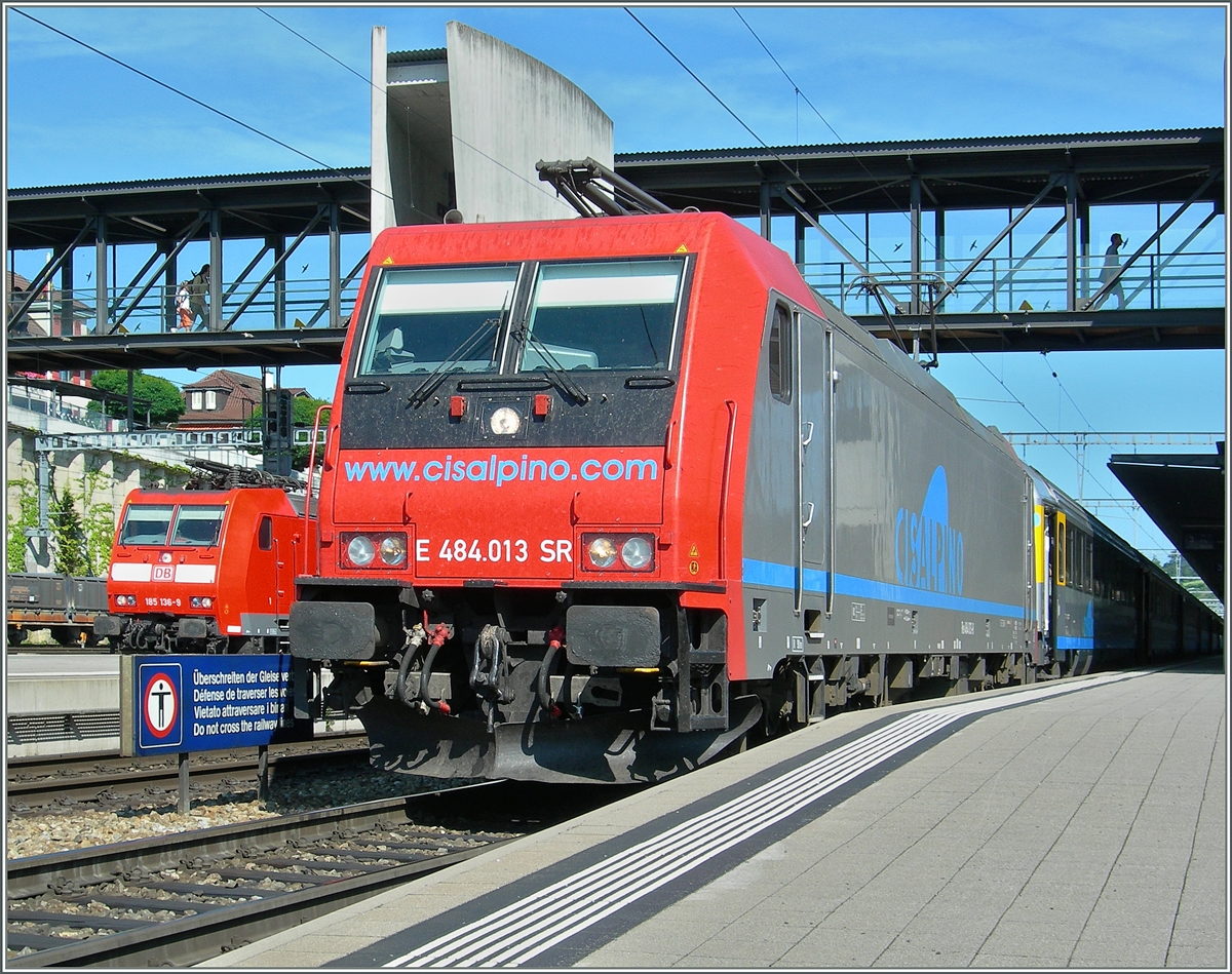 Die von der SBB an Cisalpino vermietete Re 484 013 mit einem CIS-EC nach Milano beim Halt in Spiez während links im Bild die DB 185 nach der Überholung durch den EC auf die Weiterfahrt Richtung Süden wartet. 11. Juli 2006