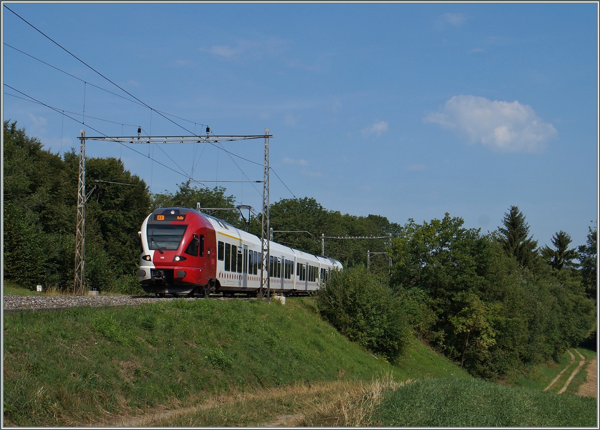 Ein TPF Flirt als RE von Fribourg nach Bulle auf dem kurzen Abschnitt des noch mit alten Fahrleitungsmasten ausgestatteten Streckenabschnitt Rosé - Neyruz der Strecke Bern - Lausanne kurz nach Rosé. 
6. Aug. 2015