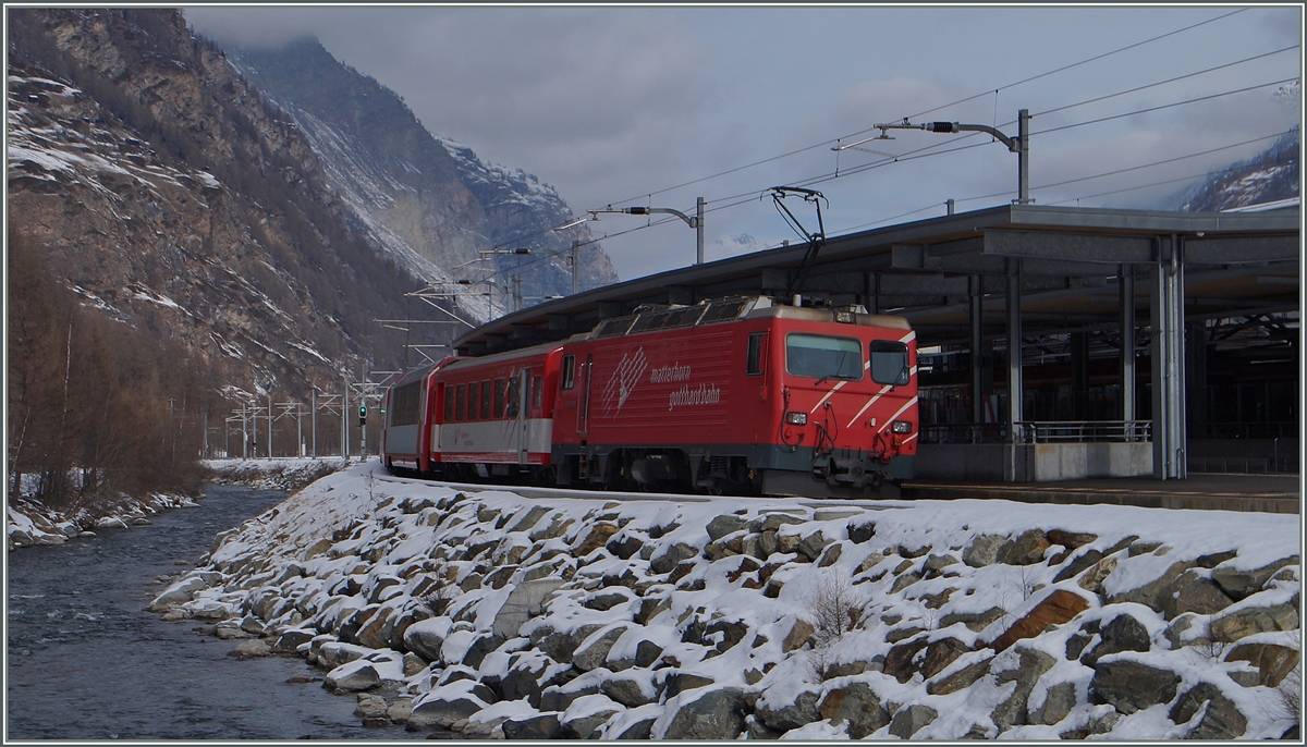 Eine HGe 4/4 mit einem Reisezug von Zermatt Richtung Visp beim Halt in Täsch.
28. Jan 2015