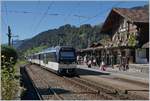 Ein MOB Alpina Triebzug erreicht den bunt blühenden Bahnhof von Saanen.