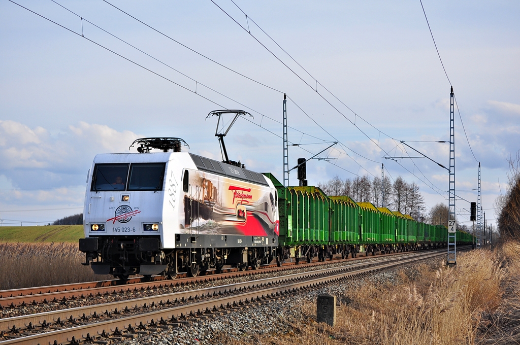 Mit einem Holzzug aus Stendal rollt die attraktive 145 023 der PRESS durch Sildemow in Richtung Rostock-Bramow.