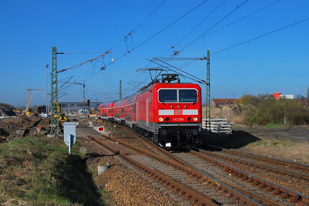 Mit einer S-Bahn nach Warnemnde rollt die frisch Hauptuntersuchte 143 250(LDX 08.04.2011) durch den im Umbau befindlichen  Hp Warnemnde Werft.