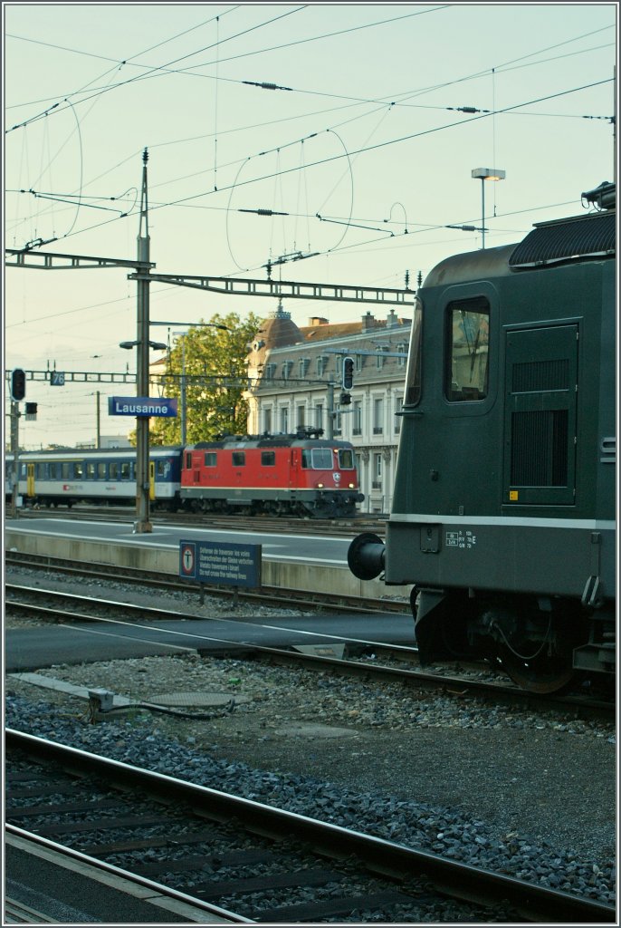 Whrend im Vordergrund nur angeschitten die grne Re 4/4 II 11309 zu sehe ist, fhrt im Hintergrund gerade eine rote Re 4/4 II mit einem Regionalzug in Lausanne ein.
24. Mai 2011