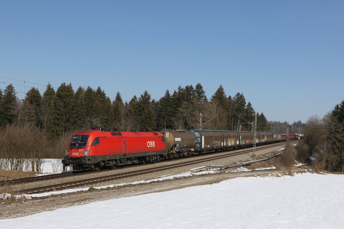 1116 057 war mit einem gemischten Gterzug am 2. Mrz 2023 bei Sossau im Chiemgau in Richtung Mnchen unterwegs.