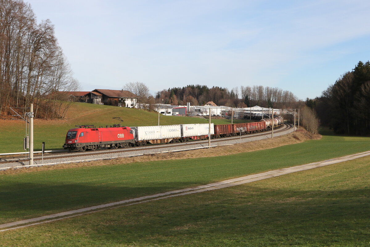 1116 135 war am 28. Dezember 2023 mit einem gemischten Gterzug bei Axdorf im Chiemgau in Richtung Mnchen unterwegs.