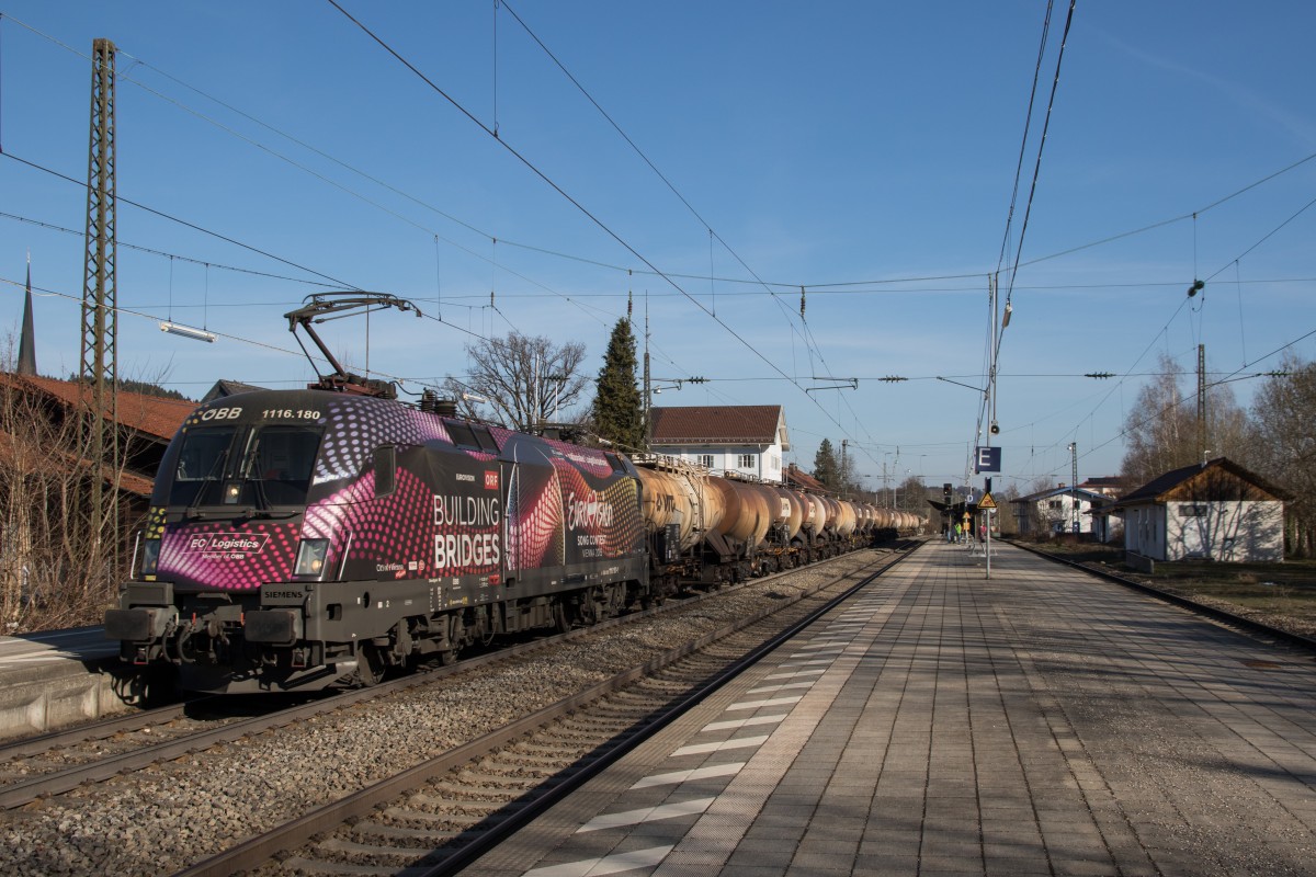 1116  180-1  Building Bridges  am 9. April 2015 mit einem Kesselwagenzug bei der durchfahrt des Bahnhofs von Prien am Chiemsee.