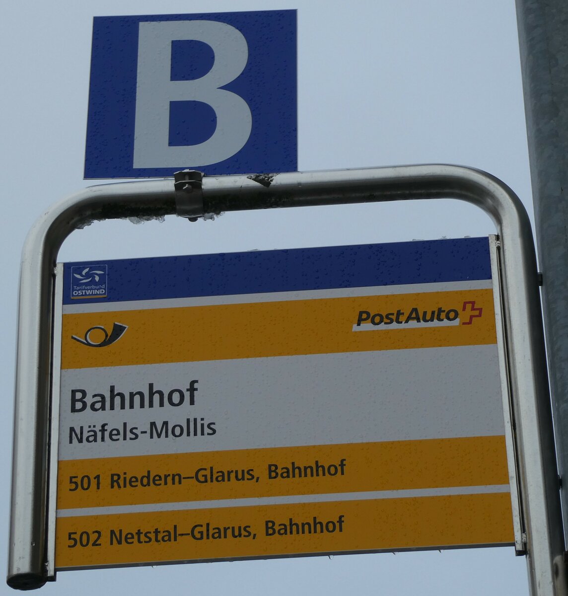 (231'965) - PostAuto-Haltestellenschild - Nfels-Mollis, Bahnhof - am 10. Januar 2022