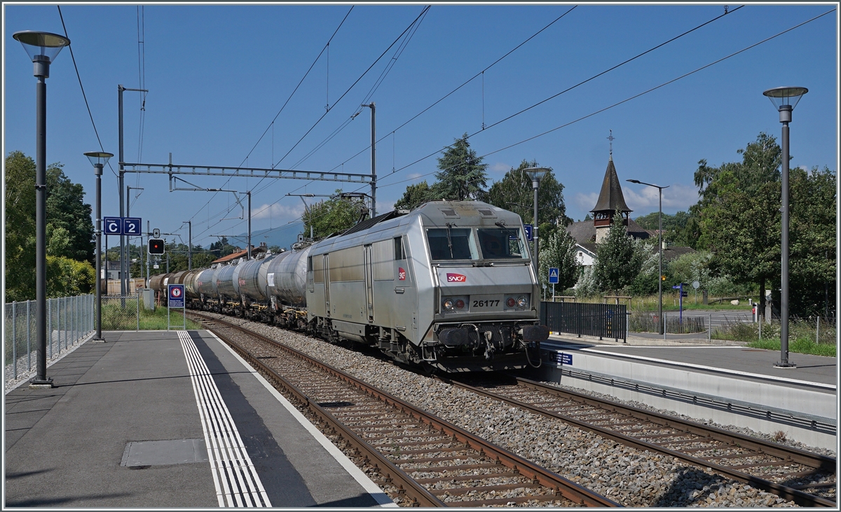Auf den ersten Blick eine typisch, zeitgemässe SBB Station, nur der Zug scheint nicht zu passen... Die SNCF BB 26177 (Sybic) fährt mit einem gemischten Güterzug auf dem Weg nach Genève La Praille durch den Bahnhof von Satigny, auf der Strecke (Bellegarde Ain) - La Plaine - Genève, die abweichend vom übrigen SBB Netz mit 25 000 Volt 50 Hertz Wechselstrom elektrifiziert ist.

19. Juli 2021 