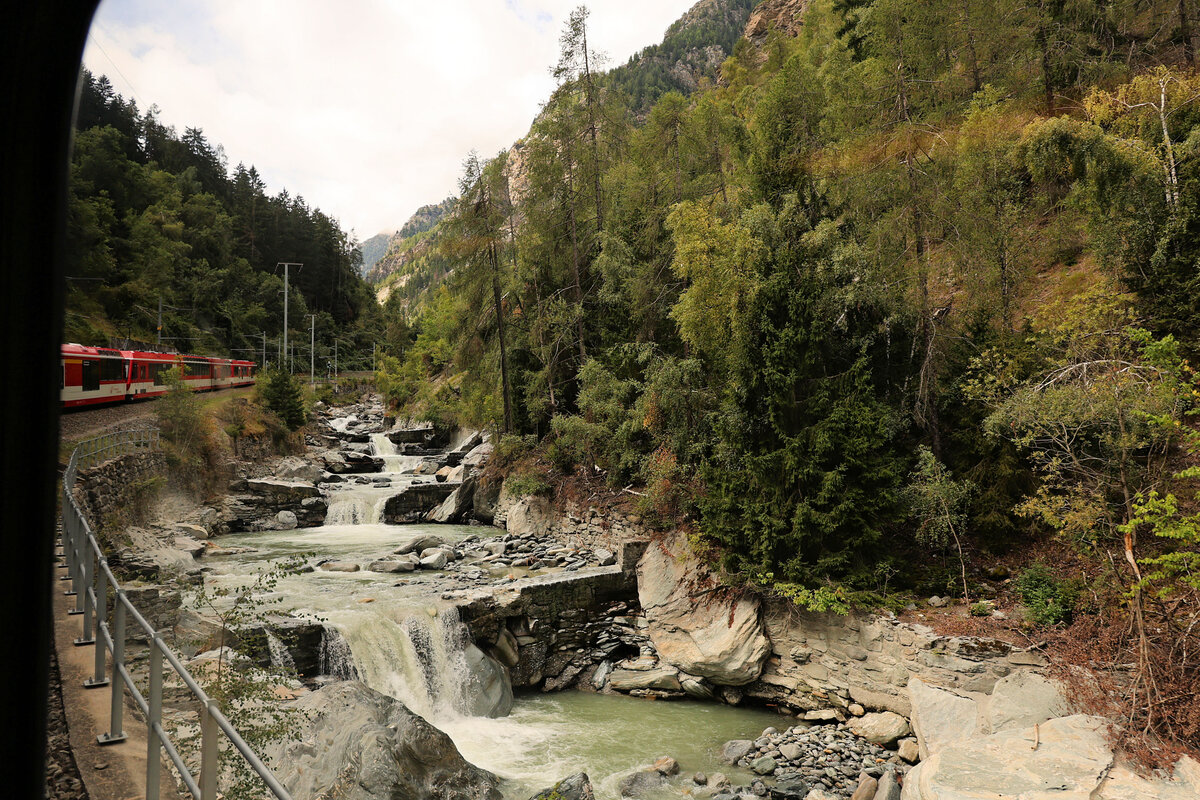 Das Problem der fixen Fenster bei der MGB. Nur noch wenige Züge führen heute noch Wagen mit senkbaren Fenstern, und so ist es kaum mehr möglich, Aufnahmen an besonders reizvollen Stellen wie die Kipfenschlucht (Strecke Visp - Zermatt) zu machen. Zu Fuss kommt man da nicht hin. So bleibt nur noch, einen möglichst langen Zug zu erwischen und wegen der meist nur schief aufnehmbaren Ansichten und den teils extremen Spiegelungen in den fixen Fenstern reichlich Gebrauch zu machen von Fotokorrekturen, Farbanpassungen, Klonen und Bildfehlerentfernungen. Eine mühsame und für gute Bilder nicht ungefährliche Sache. Im Bild ein Photo des Zuges ABt 2131 - ABDeh4/8 2025 - ABDeh4/10 2011 in der Kipfenschlucht. 30.August 2025 