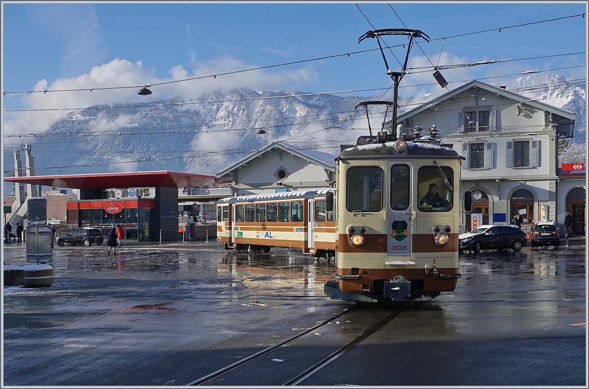 Der AL (TPC) BDeh 4/4 302 noch in der braunen AL-Farbgebung mit seinem passenden Steuerwagen überquert kurz nach der Abfahrt in Aigle den Bahnhofsplatz um dann auf der Strasse bis Aigle-Dépôt-AL Richtung Leysin zu fahren.
 29. Jan. 2019