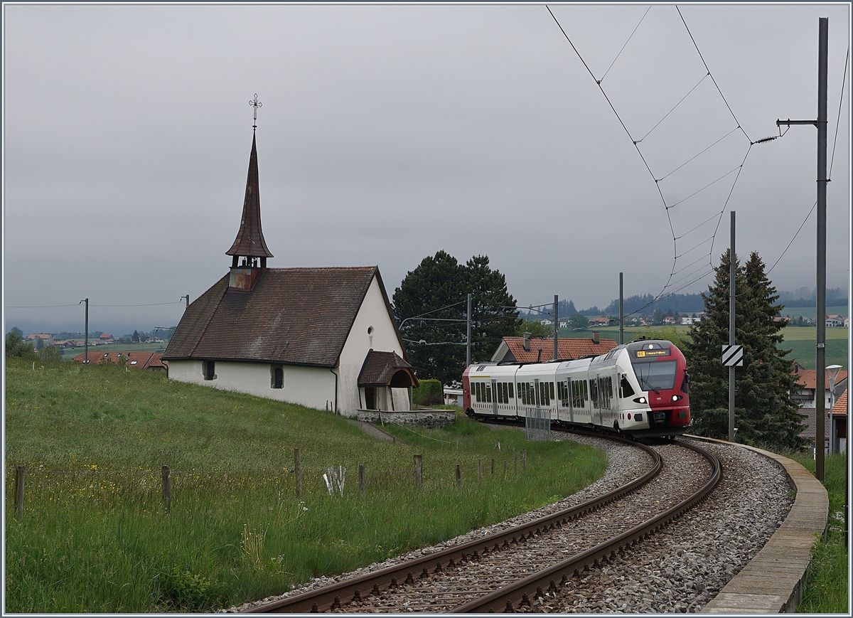Der TPF RABe 527 193 als RE von Bulle nach Fribourg bei der  Chappel de Vaulruz  unter der herrlichen  windschiefen  Fahrleitung. 

12. Mai 2020