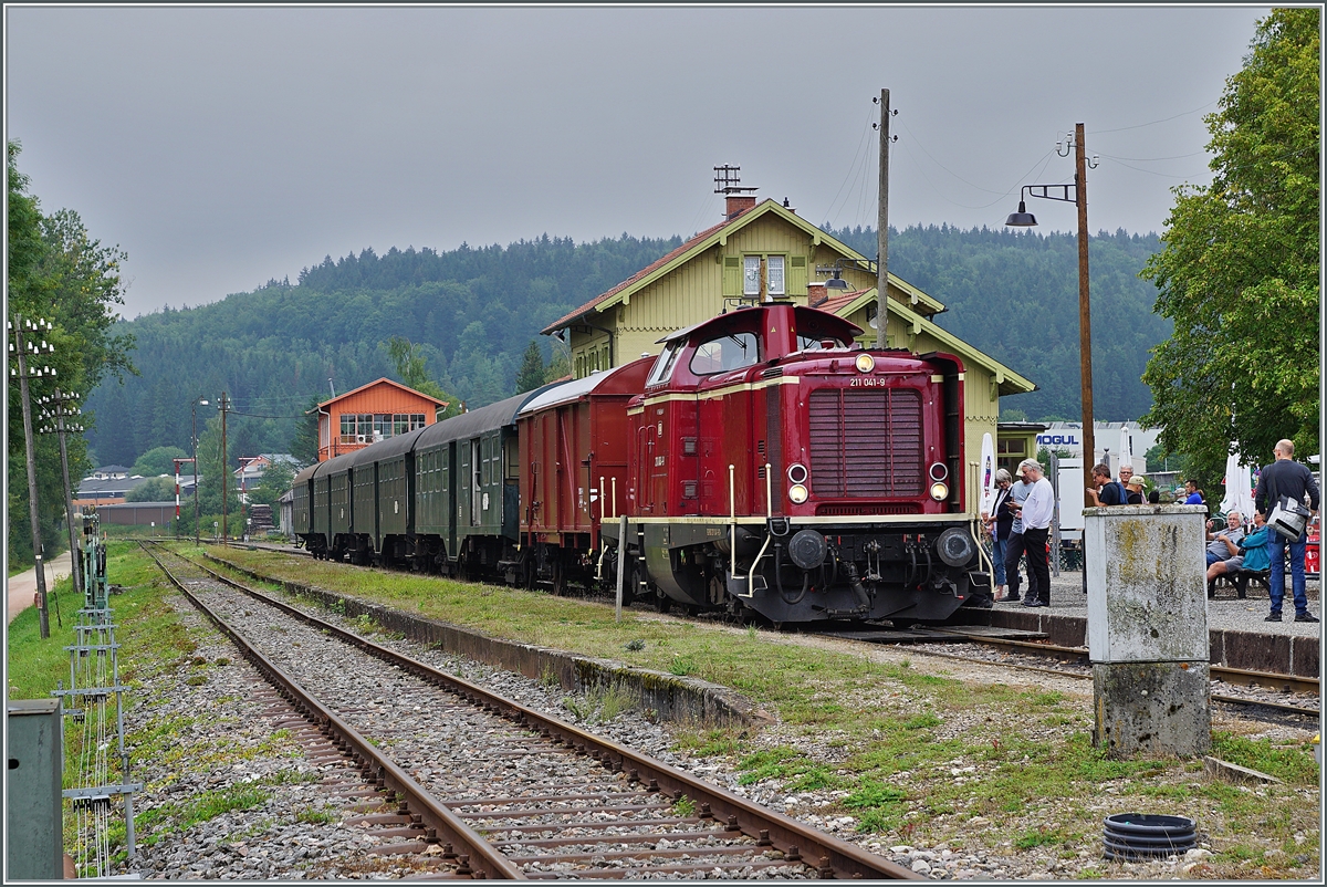 Die Diesellok 211 041-9 (92 80 1211 041-9 D-NeSA) mit einem stimmigen Zug aus Umbauwagen wartet als  Morgenzug  im Bahnhof Zollhaus Blumberg auf die Abfahrt. Die Aufnahme entstand beim offenen Bahnübergang.

27. August 2022