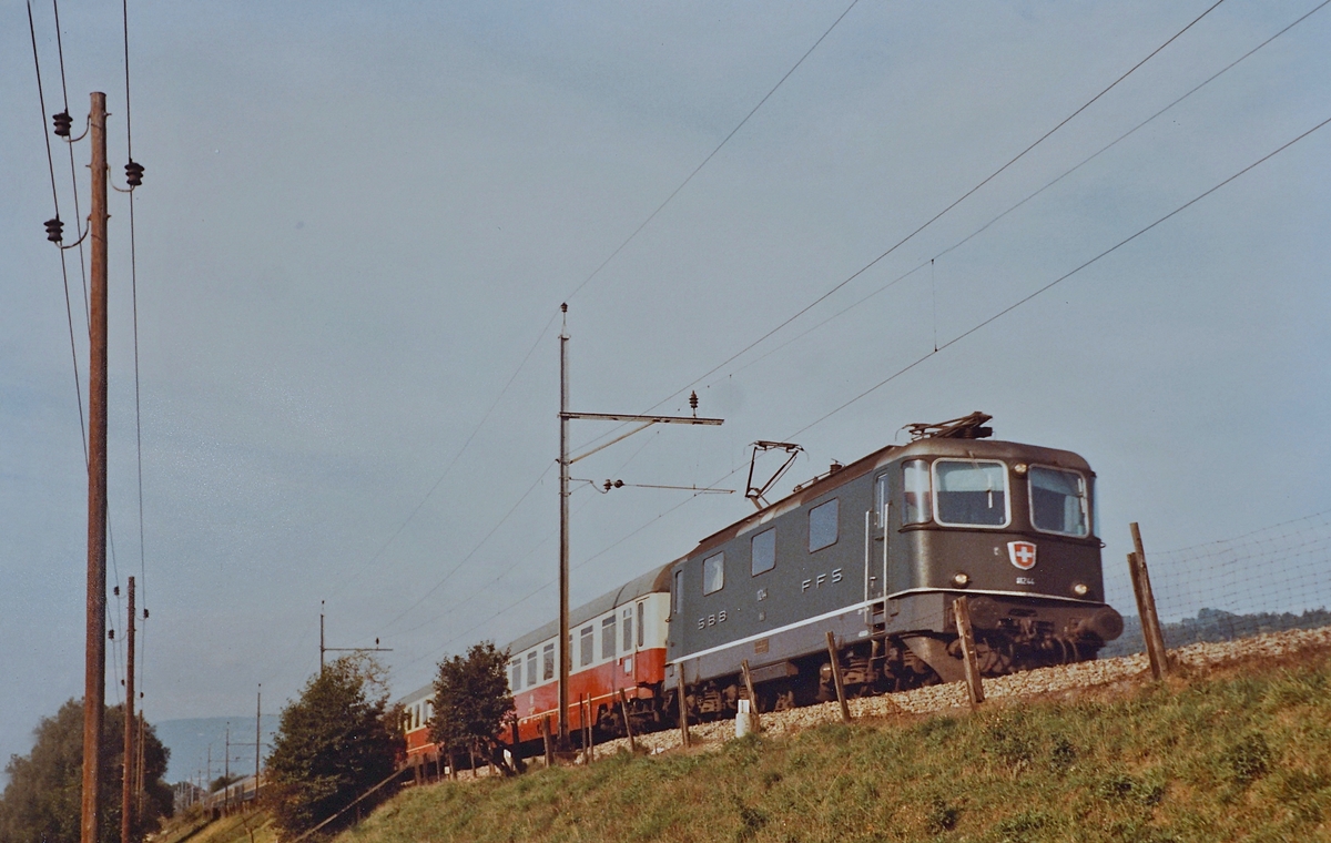 Die SBB Re 4/4 II 11244 ist mit dem IC  Mont Blanc  (Cebère) - Genève - Hamburg zwischen Lengnau und Grenchen Nord unterwegs. 

Analogbild vom September 1984
