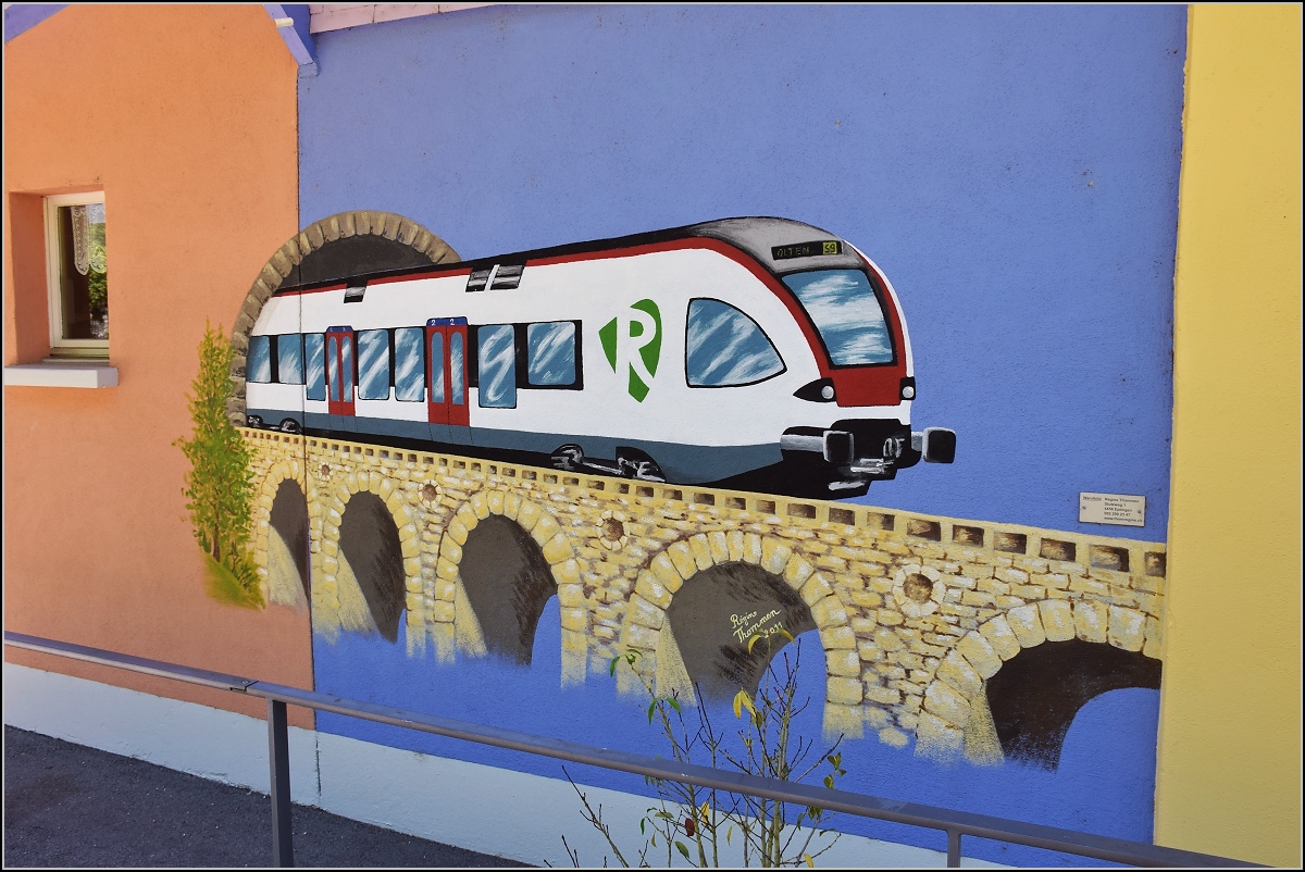 Die Umleitungen �ber das L�ufelfingerli ziehen nat�rlich den Fotografen an die Strecke zur Erkundung. Da f�llte einem in Sommerau das Kleinod von R�gine Thommen  an den Stationsgeb�uden auf. Ein Flirt, der zwar nicht auf der Linie f�hrt, aber mit dem  Emblem ein klares Bekenntnis zur S-Bahn Basel, die von den Verantwortlichen gegen die Bev�lkerung nicht abgeschafft werden konnte. Die Webseite der K�nstlerin findet sich unter http://www.thomregine.ch , wo auch weitere Werke von ihr gezeigt sind. Das Bild darf mit ihrem freundlichen Einverst�ndnis hier gezeigt werden. Sommerau, August 2018.