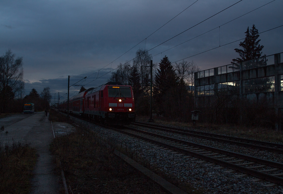 Kurz bevor es am frühen Abend des 11.01.16 völlig finster wurde, konnte 245 014-6 mit ihrem Doppelstockzug nach Mühldorf in Poing fotografiert werden. Im Hintergrund machen ein Linienbus und sein Fahrer gerade eine kurze Pause.