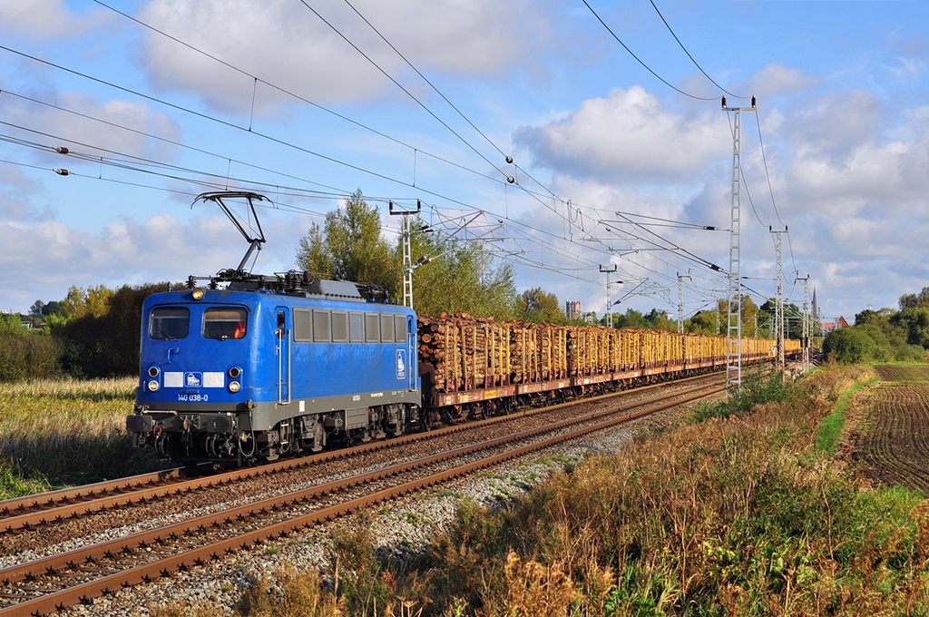 Mit einem Holzzug nach Niedergörne hat die 140 038 vor wenigen Minuten Rostock-Bramow verlassen,nach knapp 15 Minuten Fahrt hat der Zug bereits Rostock hinter sich gelassen und fährt nun durch Sildemow auf der KBS 100 in Richtung Schwerin. 