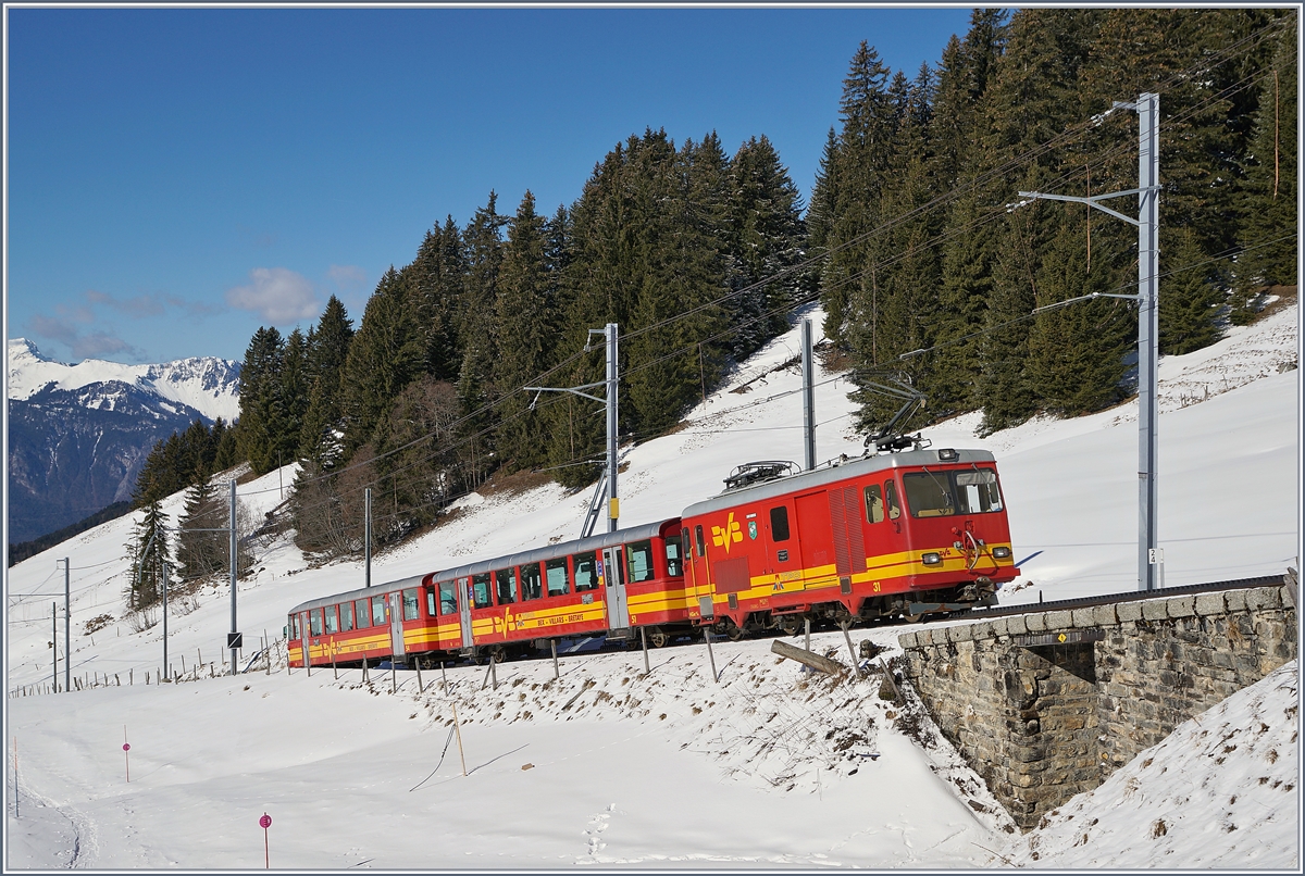 Mit ihrem farblich passenden Zug fährt die BVB TPC HGe 4/4 31 bei Col du Soud Talwärts nach Villars sur Ollon.

5. März 2019