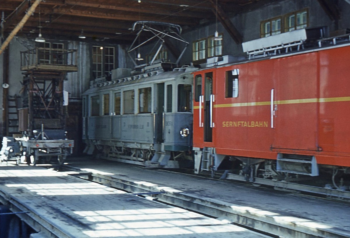 Sernftalbahn: Blick von der öffentlichen Strasse ins offenstehende Werkstattgebäude in Engi. Personentriebwagen 4 und der Gepäcktriebwagen 22. 13.April 1967. 