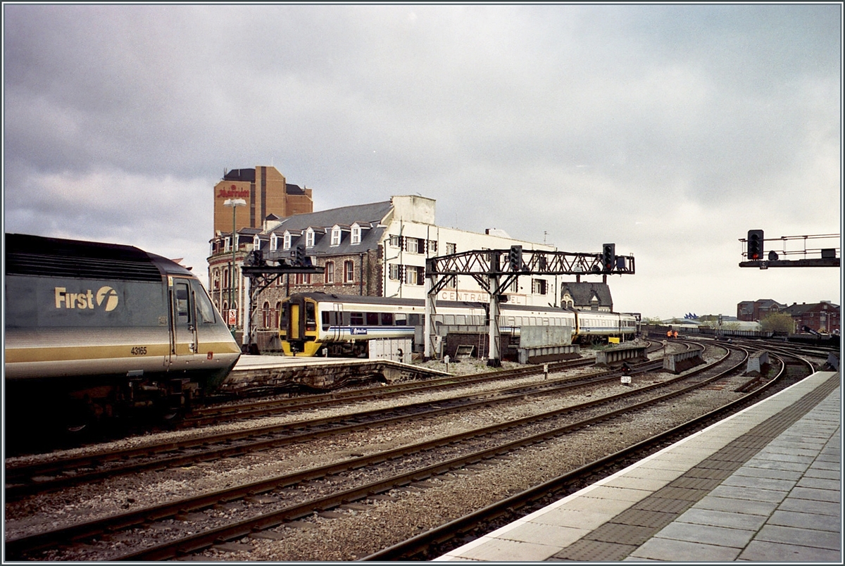 Während ein  First  HST 125 Class 43 in Cardiff auf die Abfahrt wartet erreicht im Hintergrund ein Class 158 den Bahnhof.

Analogbild vom November 2000