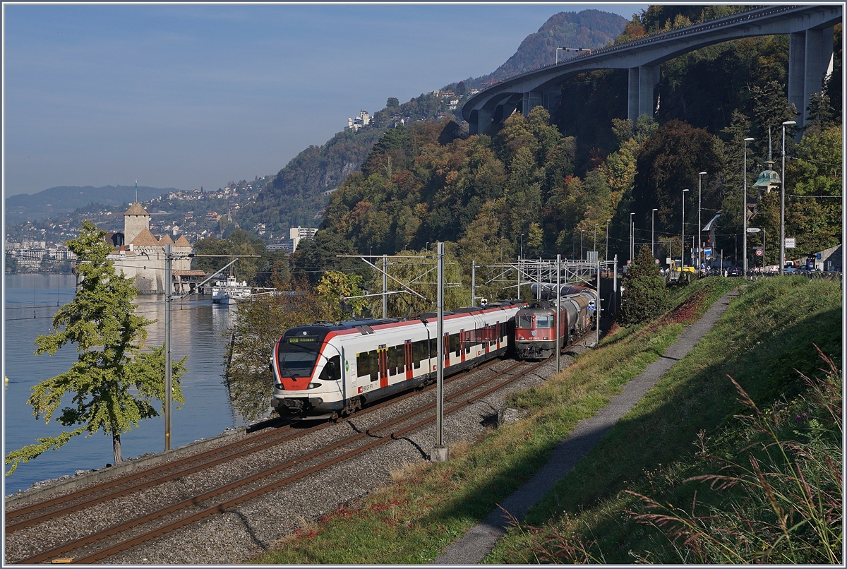 Während ein Flirt beim Château de Chillon Richtung Lausanne fährt, kommt aus der Gegenrichtung ein Güterzug mit einer SBB Re 4/4 II angefahren. 

18. Okt. 2018