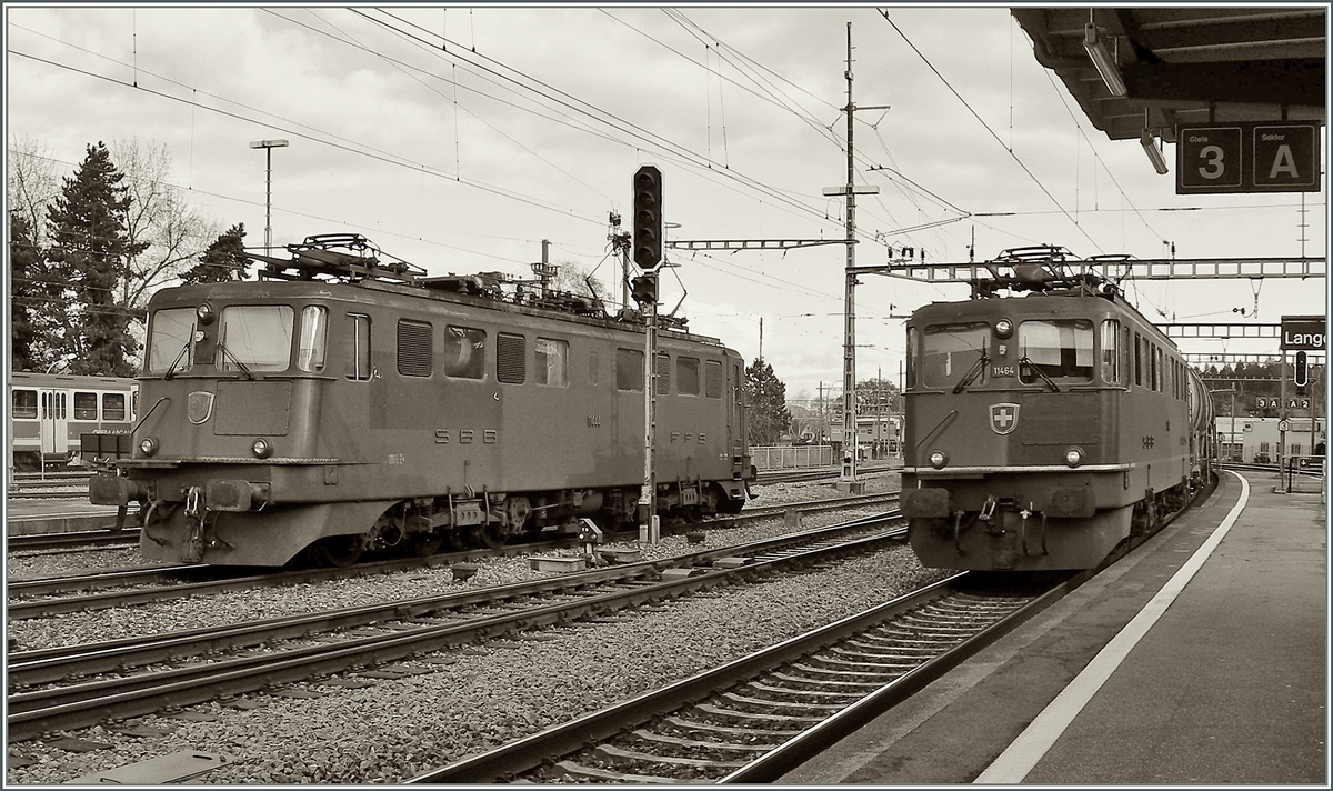 Während die grüne Ae 6/6 11444 in Langenthal auf neue Aufgaben wartet, fährt die rote Ae 6/6 11464 mit ihrer Güterzug ohne Halt durch. 22. November 2006  