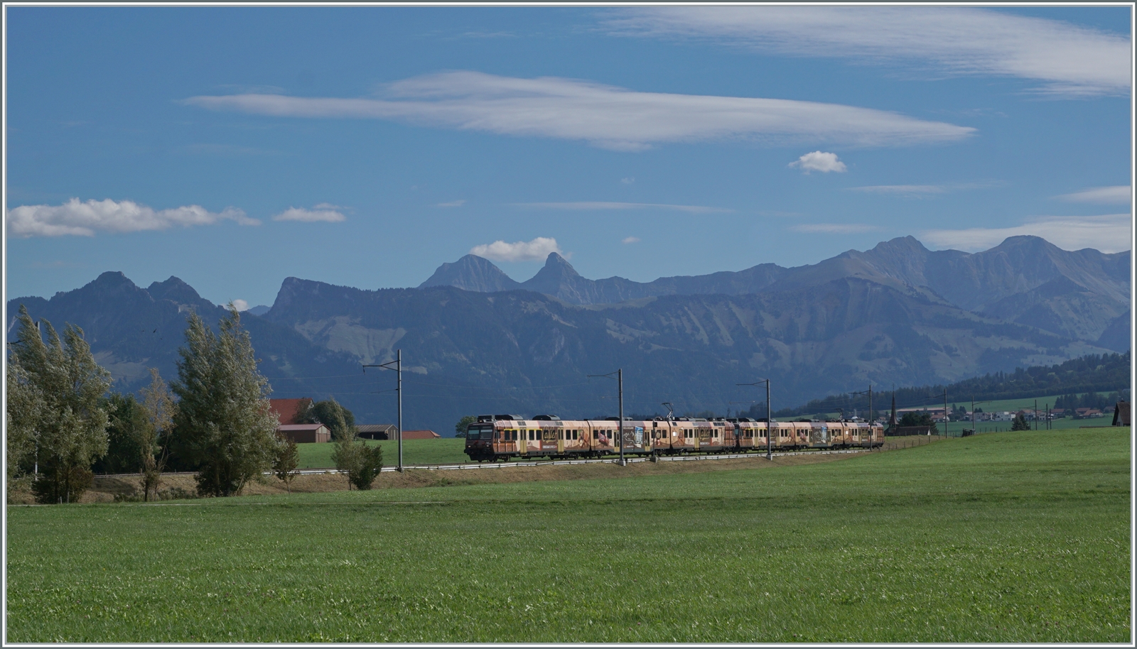 Die beiden TPF RBDe 560 245 und 235 Domino Züge in der  Chocolat Express  Werbung sind als RE 3825 von Broc-Farbique nach Bern unterwegs. Das Bild entstand zwischen Vaulruz und Sâles vor dem Hintergrund der Fribouger Alpen.

29. September 2023