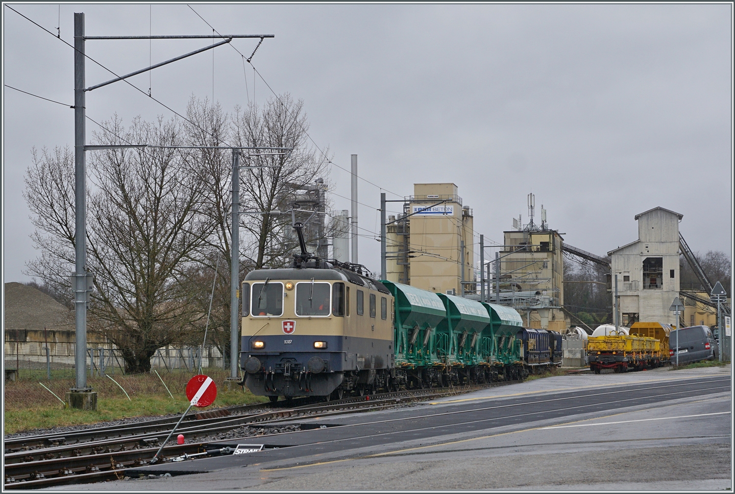 Die IRSI/IGE  Rheingold  Re 4/4 II 11387 (Re 421 387-2) kommt mit ihrem Güterzug nach Apples am Haken aus dem Industrie Gelände bei Gland angefahren. 

22. Februar 2024