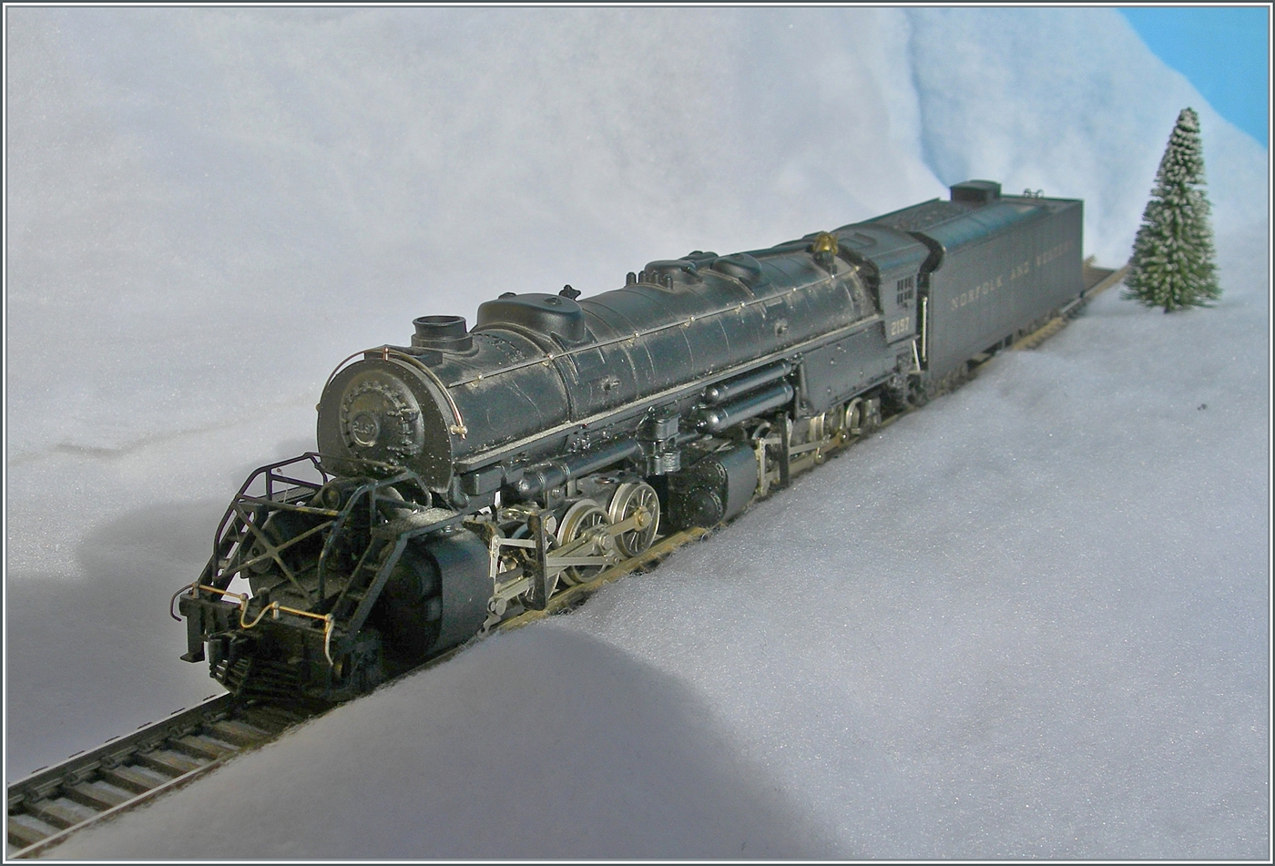 Die selbst in H0 mächtige Mallet Dampflok 2-8-8-2 - Y6b 2197 der Norfolk & Western kämpft sich durch den Schnee. Die Konstruktion der Mallet Vorbildloks Loks basiert Angaben, welche die U.S.R.A. (United States Raitroad Administration) während des Ersten Weltkriegs eingeführt hat. Die die Loks der Klasse Y6b wurde ab 1936 ausgeliefert. Grundsätzlich wurde die Klasse Y6b so konstruiert, dass sie schwere Güterzug mit 30 mp/h ziehen konnte, doch unter guten Bedingungen konnten auch bis zu 50 mp/h erreicht werden. 

Das Modell dieser Gelenklokomotive Typ Mallet „Y 6 b“ der  Norfolk & Western  dürfte gut 50 bis 60 Jahre alt sein und ist eine von der Grüsse her sehr beeindruckende Modellumsetzung. Nicht ganz logisch scheint mir, weshalb der Motor bei soviel Platz in das Führerhaus gequetscht wurde, um dann durch lange kardanischen Wellen die weit entfernten  Drehgestelle  anzutreiben. Der Tender ist vorbildgerecht mit zwei dreiachsigen  Buckeye -Drehgestellen ausgestattet, die auch zur Stromabnahme herangezogen werden. 

Das Modell dürfte gut zwanzig bis dreissig Jahre lang nicht mehr gefahren sein, nachdem ich das Modell zerlegt und bewegliche Teile entfettet und neu eingeölt habe, fährt es seit gestern wieder, auch wenn mir für den Auslauf des mächtigen Modell sowohl die Wagen als auch die Strecke fehlt. 

12. Jan. 2025