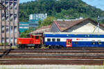 Die SBB Tmf 232 302-0 (Tmf 98 85 5 232 302-0 CH-SBB) rangiert am 11.07.2022 einige Personenwagen beim Bahnhof Olten (Aufnahme aus einem Zug durch die Scheibe).

Die dieselhydraulische Rangierlok (Rangiertraktor) wurde 1975 von Schweizerische Lokomotiv- und Maschinenfabrik (SLM) in Winterthur unter der Fabriknummer 5064 gebaut und als Tm IV 9665 an die Schweizerische Bundesbahnen (SBB / CFF / FFS) geliefert. Im Jahr 1999  ging sie an die SBB Infrastruktur. 

Im Jahr 2013 hat die SBB Infrastruktur das Retrofit von 15 Tm IV Rangierloks in Auftrag gegeben.  So wurde auch diese Lok 2013 einer umfassenden Modernisierung (Retrofit), im SBB Industriewerk Biel, unterzogen. So gehören unter anderem ein verbrauchsarmer Caterpillar-Dieselmotor, ein Partikelfilter, eine zusätzliche Ladeluftkühlanlage, eine neue Fahrzeugsteuerung, eine neue Sicherheitssteuerung, Zugsicherungen, die Funkfernsteuerung und schließlich die Änderung der Bordspannung von 36 auf 24 Volt zum Umfang dieser Modernisierung. Durch die Möglichkeit der Mehrfachtraktion sowie der Funkfernsteuerung ist ein effizienter und wirtschaftlicher Betrieb möglich. So werden die bereits über 40-jährigen Tm IV als Tmf 232.3 viele weitere Jahre Dienst auf dem Schweizer Schienennetz leisten können. Die Tmf 232.3 verfügen zusätzlich, gegenüber den Tm 232 über eine Vielfachsteuerung, GSM-R Funk und Baufunk.

Fahrzeugrahmen
Eine sehr robuste geschweißte Rahmenkonstruktion bildet das Grundgerüst des Fahrzeuges, auf dem sich einerseits die Führerkabine, welche fest mit dem Rahmen verschweißt ist, sowie alle notwendigen Unterlagen und Konsolen für die Aufnahme der einzelnen Komponenten.
Die Unterseite besteht aus zwei massiven Längsträgern, in welchen
die zwei Achshalter eingelassen sind und die Bremskomponenten
aufnehmen. Diese sehr robuste Konstruktion hat eine gute Krafteinleitung zur Folge.

An beiden Enden des Triebfahrzeuges befindet sich je eine Stirn-
platte, worauf die Puffer angeschraubt sind. Die Zugvorrichtung ist
mit einem Federelement ebenfalls an der Stirnplatte befestigt.

Zug- und Stossvorrichtung
Die Zugvorrichtung besteht aus dem Zughaken und einer Schraubenkupplung, bei der Tmf 232 ist zusätzlich ist eine Rollwagenkupplung angebracht. Die Stoßvorrichtung besteht aus Puffern ohne Deformationselemente, welche direkt auf der Stirnplatte angeschraubt sind.

Fahrwerk
Das Fahrwerk besteht aus zwei Radsätzen mit Scheibenrädern. Auf
der Außenseite der Achswellen sind die Achslagergehäuse mit
Zylinderrollenlager angebracht. Die Achslagergehäuse sind mittels Manganplatten im Achshalter geführt. Der Fahrzeugrahmen stützt sich über vier Blattfederpakete ohne Lastausgleich auf die Achslagergehäuse ab.

Kraftübertragung
Das Drehmoment wird vom Motor mittels einer Kardanwelle auf das Voith-Turbowendegetriebe, dann auf das Verteilgetriebe und schließlich über Kardanwellen auf die Achsen übertragen.

Turbowendegetriebe
Das Voith-Turbogetriebe ist ein vollautomatisch arbeitendes, hydrodynamisches Strömungsgetriebe für die Kraftübertragung zwischen Dieselmotor und Triebachsen. Es besteht im Wesentlichen aus zwei hydrodynamischen Wandlern, bei welchen die Kraftübertragung durch die Massenkräfte einer Betriebsflüssigkeit (Mineralöl) erfolgt.

Die zwei hydrodynamischen Wandler und bestehen aus je
einem Pumpenrad, Turbinenrad und feststehendem Leitrad. Im
Pumpenrad wird die vom Dieselmotor abgegebene mechanische Energie in Strömungsenergie umgewandelt. Im nachfolgenden Turbinenrad wird durch Verzögerung und Umlenkung der
Flüssigkeitsmaße wieder mechanische Energie zurückgewonnen.
Das im Turbinenrad entstehende Drehmoment ist abhängig vom
Grad der Umlenkung der Betriebsflüssigkeit. Die Umlenkung und
damit das Turbinendrehmoment ist bei festgehaltener Turbine am
größten und fällt mit zunehmender Turbinendrehzahl ab. Das
Leitrad als dritter Hauptbestandteil eines hydrodynamischen
Wandlers hat die Aufgabe, die Zulaufrichtung zum Pumpenrad
unabhängig von der Abströmrichtung des Turbinenrades konstant
zu halten, so dass die Leistungsaufnahme des Pumpenrades von
der Turbinendrehzahl nicht beeinflusst wird. Das Leitrad ermöglicht
auf diese Weise eine Drehmomentwandlung und nimmt das Differenzmoment zwischen Pumpenrad und Turbinenrad auf.

Motor
Der Dieselmotor ist ein wassergekühlter, verbrauchsarmer Caterpillar- 6 Zylinder-Viertakt-Dieselmotor mit Ladeluftkühlung (Industriemotor), welcher bei 1.600 U/min eine Leistung von 280 kW abgibt. Er erfüllt die Euro-III<A Norm bezüglich den Abgaswerten. 

Technische Daten des Dieselmotores:
Fabrikat: Caterpillar vom Typ C13 Acert
Kühlung: Wasser
Arbeitsverfahren: Viertakt
Verbrennungsverfahren :Direkteinspritzung
Aufladung:  Abgas-Turboaufladung mit Luft-Luft-Ladeluftkühlung
Zylinderzahl / Bauform:  6-Zylinder Reihen-Motor
Verdichtungsverhältnis 17,3:1
Kolbendurchmesser / -hub: 130 mm / 157 mm
Hubraum: 12,5 Liter
Motorgewicht: 1.350 kg
Leerlaufdrehzahl:  600 U/min
Maximale Drehzahl: 1.600 U/min
Maximales Drehmoment: 1.897 Nm bei 1.400 U/min
Abgasanlage Partikelfilte

Der Dieselmotor ist über elastische Gummilager auf dem Fahrzeugrahmen montiert. Die beiden Brennstofftanks mit total ca. 850
Liter Inhalt sind im Untergestell montiert. Die Abgasanlage inkl. Partikelfilter und Kompensatoren wird durch
den Vorbau und die Kabinenstirnwand geführt

Abgasanlage
Die Triebfahrzeuge sind mit einem Partikelfilter ausgerüstet, der
anstelle eines Schalldämpfers in die Abgasleitung eingebaut ist. Der
Filter enthält eine Filterzelle aus Siliziumkarbid-Waben und ist für die
Reinigung der motorischen Abgase aus Diesel-Verbrennungsmotoren ausgelegt. Alle dem Abgasstrom ausgesetzten Teile sind in
Edelstahl ausgeführt. Damit werden auch bei hohen Temperaturen
Korrosionsschäden verhindert.

Prinzip des Partikelfilters
Das Abgas strömt von der Rohgasseite in die Filterzelle aus Siliziumkarbid, lagert die Partikelfracht an der Zelle ab und durchströmt
die Zellwand zur Reingasseite. Der Filter darf bei Abgastemperaturen bis zu 600°C eingesetzt werden. Der Betrieb des Rußpartikelfilters läuft komplett selbstständig ab. Die Filtermodule verfügen über eine katalytische Beschichtung, welche die Abbrandtemperatur je nach Rußfracht der aufgefangenen Rußpartikel auf unter 300°C bringt

Bremsen
Das Triebfahrzeug verfügt über die folgenden Bremssysteme:
• eine direkt wirkende, elektropneumatische Rangierbremse
• eine indirekt auf die Anhängelast wirkende Anhängerbremse
• eine elektropneumatisch gesteuerte Festhaltebremse
• eine elektropneumatisch gesteuerte Schleuderbremse
• eine Nachbremse
• eine Handbremse

Die Bremsen werden elektropneumatisch gesteuert. Je Fahrzeugseite ist ein Bremszylinder mit dazugehörigem Gleitschutzventil und Bremsgestänge angeordnet. Jedes Rad wird beidseitig durch je einen Bremsklotz gebremst. Die Bremsklotzabnützung wird durch
einen Bremsgestängesteller (Stopex) je Bremszylinder ausgeglichen.

Rangierbremse
Die Rangierbremse wirkt nur auf das Triebfahrzeug und ist als
direkte Bremse ausgeführt. Die direkte Bremse wird mit dem Fahr-
/ Bremshebel betätigt. Ein Druckregler begrenzt den Druck auf höchstens 3,5 bar. Die Rangierbremse kann nicht ausgeschaltet werden

TECHNISCHE DATEN:
Spurweite: 1.435 mm
Achsfolge: B (2/2)
Länge über Puffer: 7.670 mm
Achsstand: 3.570 mm
Treibraddurchmesser: 950 mm (neu) / 870 mm (abgenutzt)
Breite: 3.150 mm
Höhe: 4.200 mm
Gewicht: 30 t
Leistung Dieselmotor:  280 kW
Max. Drehmoment Dieselmotor: 1.870 Nm
Maximale Anfahrzugkraft am Rad: 90 kN
Dauerzugkraft am Rad: 60 kN
Höchstgeschwindigkeit: 30 km/h (Rangiergang) / 60 km/h (Streckengang), geschleppt 80 km/h
Kleinster befahrbarer Kurvenradius: 35 m
Brennstoffvorrat: 850 l
Bremsgewicht. 30 t
Handbremsgewicht: 10 t