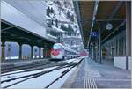Der SBB  Giruno  RABe 501 022 VAUD hat den Gotthard Tunnle verlassen und fährt durch den Bahnhof von Göschen, welcher kurz nach 12 Uhr noch im Schatten der mächtigen Berge ist und zudem