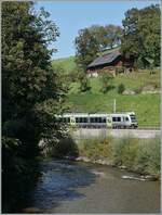 Im Vordergrund die Ilfis, im Hintergrund am steilen Hang ein Bauernhaus und in Mitte,  eingeklemmt  ein BLS RABe 535  Lötschberger  auf der Fahrt in Richtung Bern.