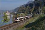 Während ein Flirt beim Château de Chillon Richtung Lausanne fährt, kommt aus der Gegenrichtung ein Güterzug mit einer SBB Re 4/4 II angefahren.